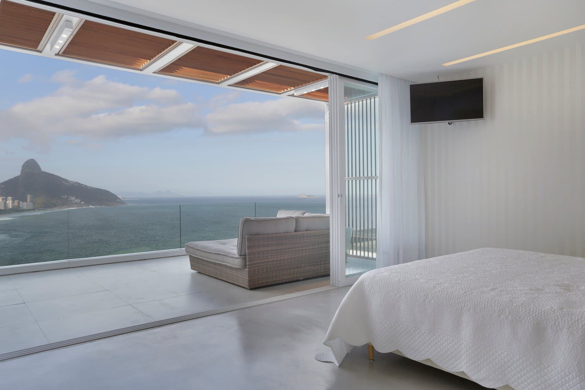 Contemporary apartment balcony with open glass doors and bright sky, Rio de Janeiro living